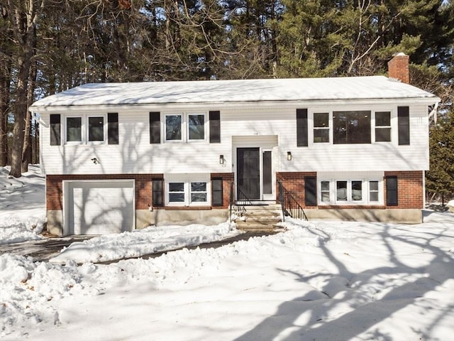 split foyer home with entry steps, a garage, a chimney, and brick siding