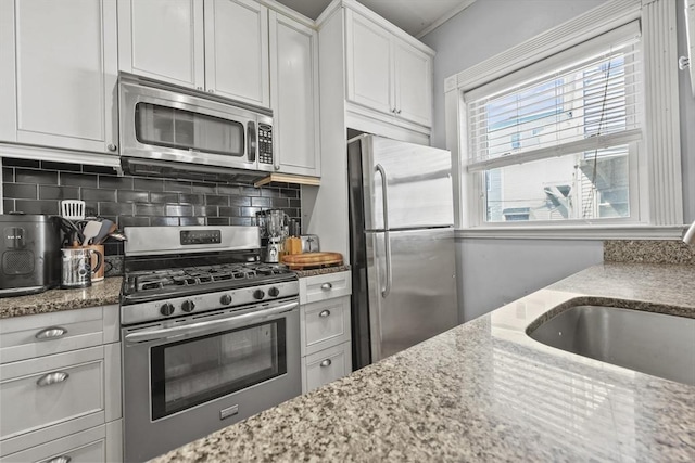 kitchen with light stone counters, a sink, and appliances with stainless steel finishes