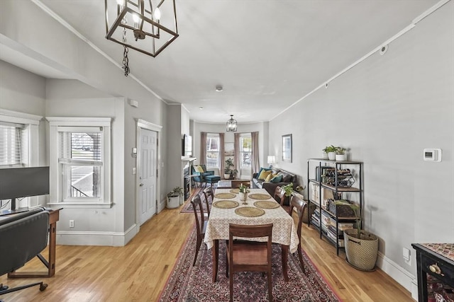 dining area featuring baseboards, light wood-style floors, crown molding, and a chandelier