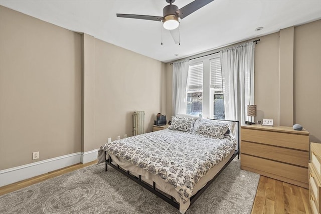 bedroom with a ceiling fan, radiator, and light wood finished floors
