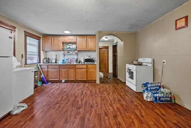 kitchen featuring a textured ceiling, white appliances, and dark hardwood / wood-style floors