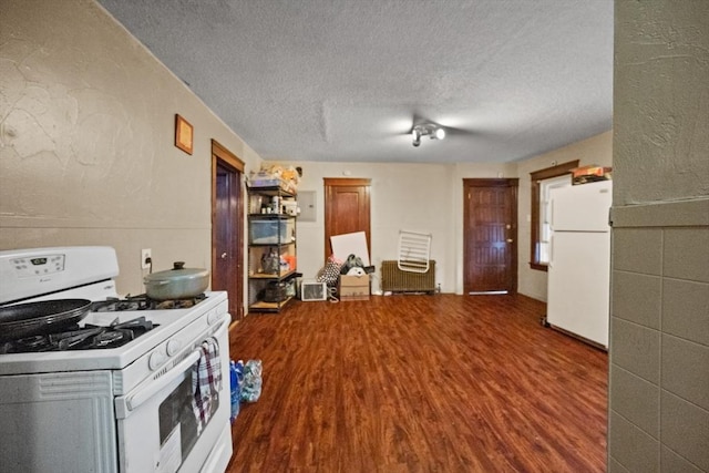 kitchen with hardwood / wood-style floors, white appliances, and a textured ceiling