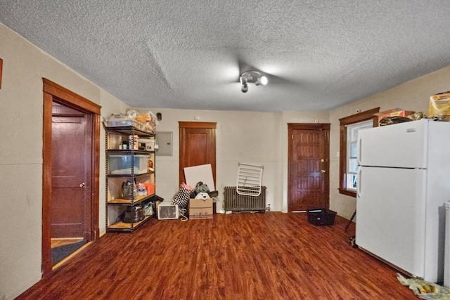 kitchen with hardwood / wood-style floors, white refrigerator, a textured ceiling, and electric panel