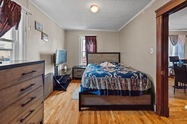 bedroom featuring radiator, crown molding, and light wood-type flooring