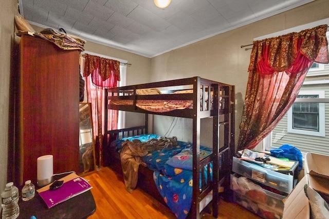 bedroom featuring hardwood / wood-style floors, ornamental molding, and multiple windows