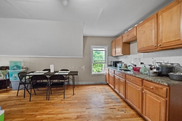 kitchen featuring decorative backsplash, stone countertops, sink, and light hardwood / wood-style flooring