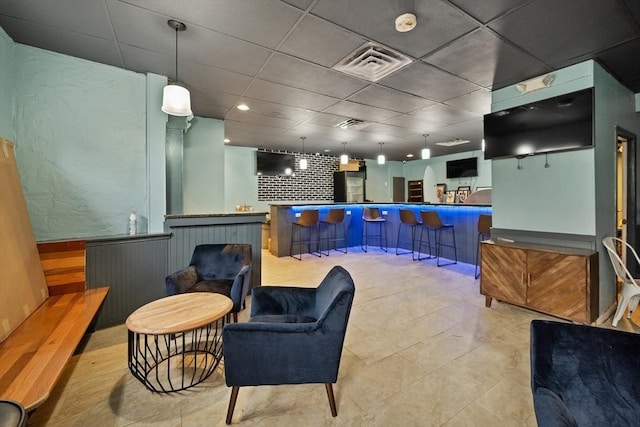 bar with a paneled ceiling, light tile patterned flooring, and hanging light fixtures