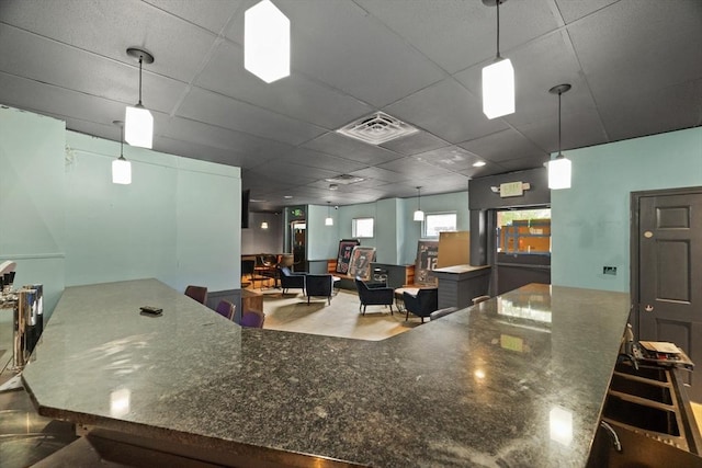 kitchen with dark stone counters, a paneled ceiling, and pendant lighting