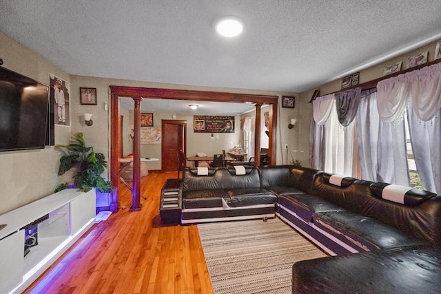 living room featuring hardwood / wood-style flooring, a textured ceiling, and decorative columns