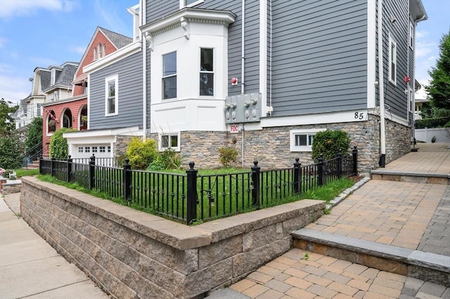 view of side of home featuring stone siding and a fenced front yard