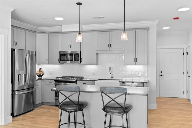 kitchen with light hardwood / wood-style floors, hanging light fixtures, stainless steel appliances, and a breakfast bar area