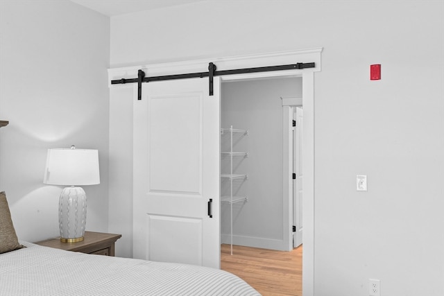 bedroom featuring a barn door, a closet, and light hardwood / wood-style flooring