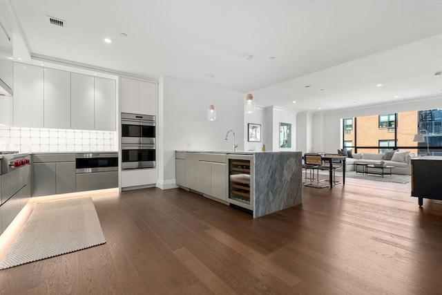 kitchen with kitchen peninsula, beverage cooler, backsplash, dark hardwood / wood-style flooring, and stainless steel double oven