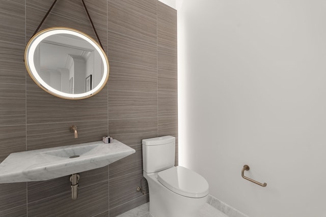 bathroom featuring toilet, tile patterned flooring, and tile walls