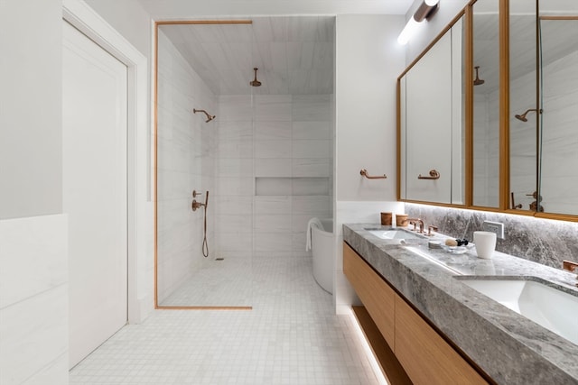 bathroom with tiled shower, tile patterned floors, tile walls, and dual bowl vanity