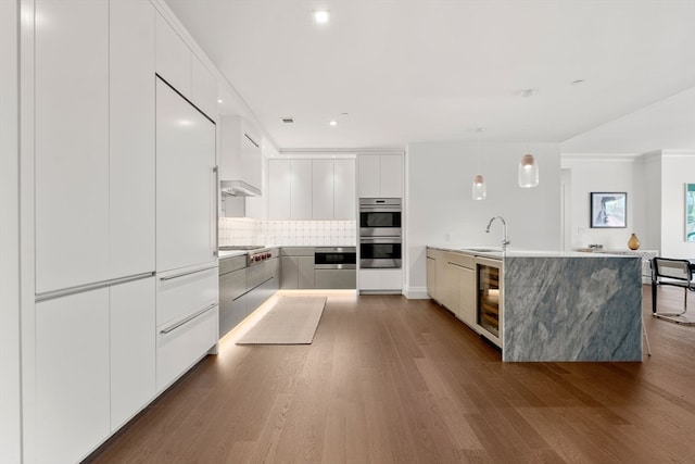 kitchen with white cabinetry, wood-type flooring, backsplash, and stainless steel appliances