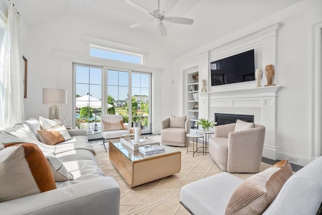 living room with ceiling fan, built in shelves, high vaulted ceiling, and a high end fireplace