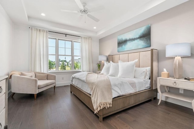 bedroom featuring dark wood-type flooring, a raised ceiling, recessed lighting, a ceiling fan, and baseboards