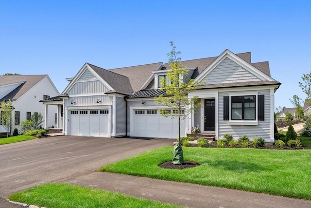 view of front of property with a standing seam roof, asphalt driveway, a front yard, a garage, and metal roof