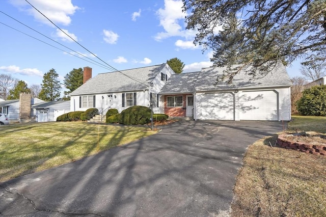 view of front of house with a front lawn, an attached garage, driveway, and a chimney