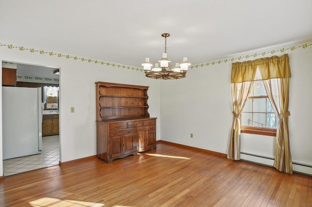 unfurnished dining area with light wood-style flooring, baseboards, and an inviting chandelier