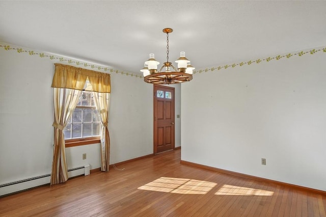 empty room with hardwood / wood-style flooring, a healthy amount of sunlight, baseboards, and a chandelier