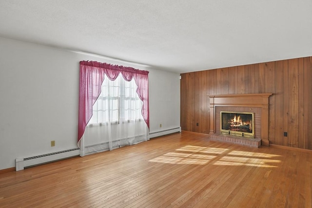 unfurnished living room with a baseboard heating unit, hardwood / wood-style flooring, a fireplace, and wood walls