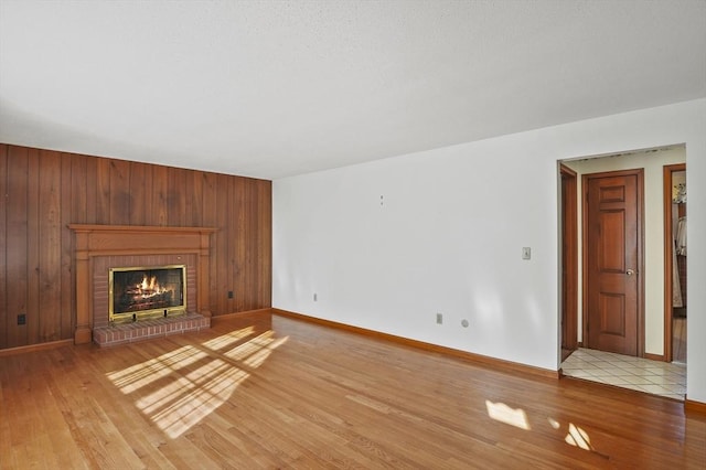 unfurnished living room featuring a fireplace, wood finished floors, and wood walls