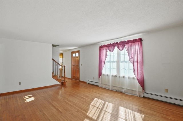 spare room featuring stairs, hardwood / wood-style flooring, baseboards, and a textured ceiling