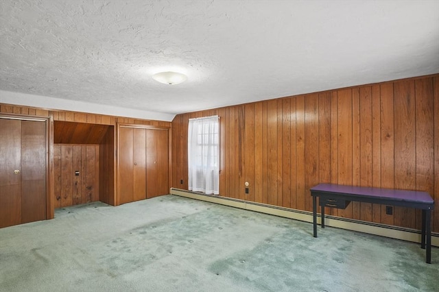 unfurnished bedroom with wood walls, a textured ceiling, and carpet