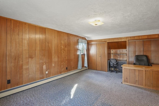 interior space featuring a textured ceiling, wooden walls, carpet, and a baseboard radiator