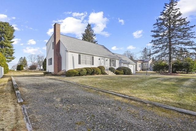 view of front of home with a garage, driveway, a chimney, and a front lawn