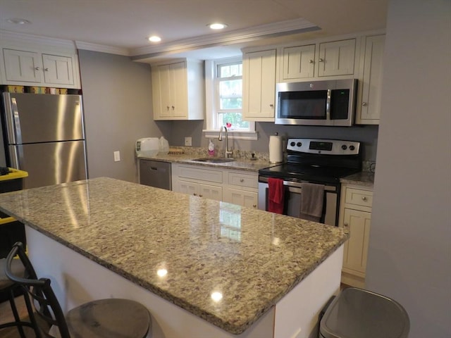 82 Main St, Blackstone, MA 01504 - kitchen with stainless steel appliances, a sink, ornamental molding, a breakfast bar, and white cabinets