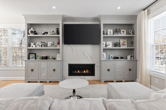 living room with light wood-style floors, a wealth of natural light, baseboards, and a premium fireplace