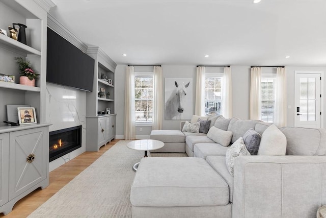 living room featuring light wood-style floors, a high end fireplace, and recessed lighting