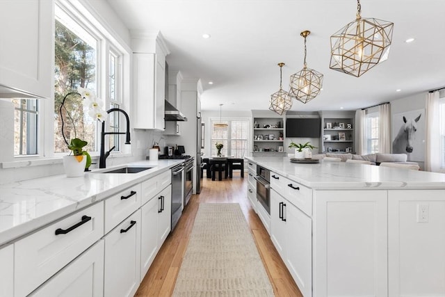 kitchen with a large island, open floor plan, white cabinetry, a sink, and light wood-type flooring