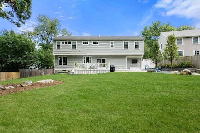 back of property with a lawn, fence, and a wooden deck