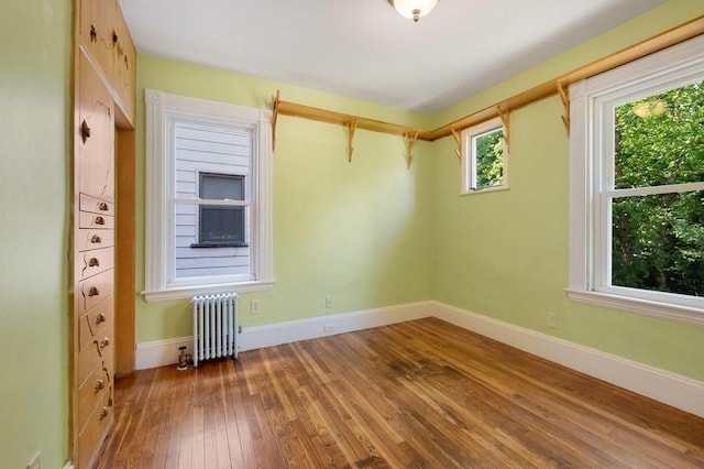 spare room with radiator, hardwood / wood-style floors, and baseboards