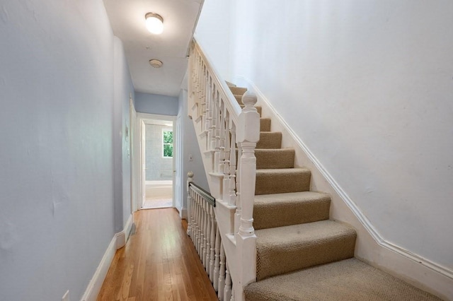 stairway with wood finished floors and baseboards