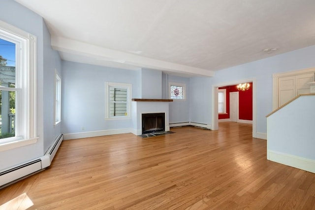 unfurnished living room with baseboard heating, a chandelier, light wood-style flooring, a fireplace with flush hearth, and baseboards