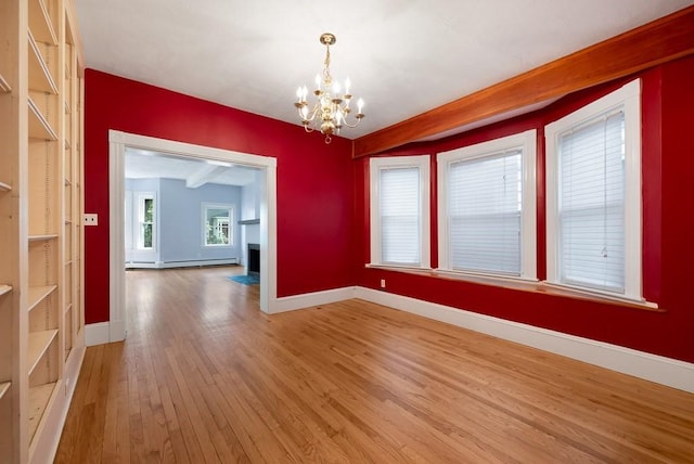 empty room featuring a chandelier, light wood finished floors, baseboards, a fireplace, and a baseboard heating unit
