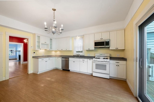 kitchen with stainless steel appliances, a chandelier, dark countertops, light wood-type flooring, and baseboards
