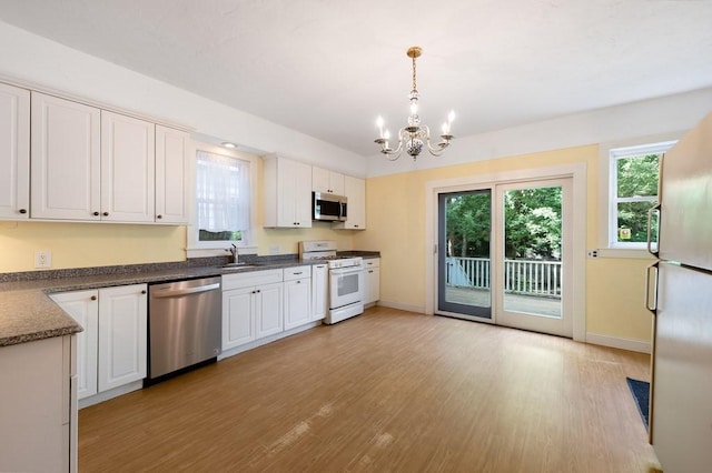 kitchen with appliances with stainless steel finishes, a chandelier, light wood-style floors, baseboards, and healthy amount of natural light
