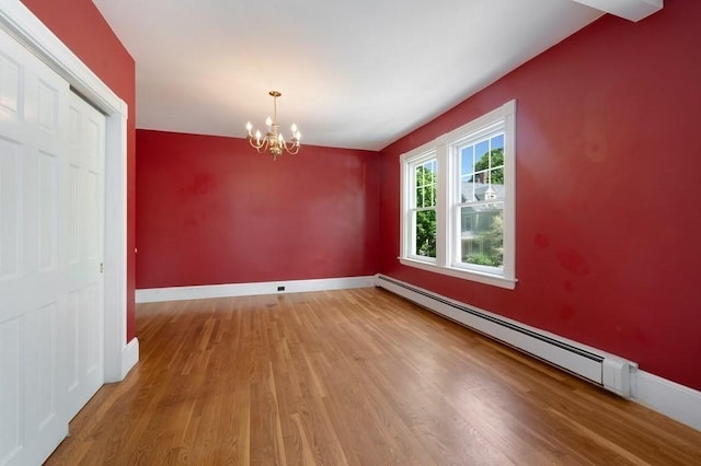 unfurnished dining area featuring wood finished floors, a chandelier, a baseboard radiator, and baseboards