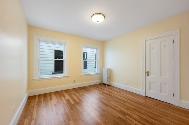 spare room with radiator heating unit, wood finished floors, and baseboards