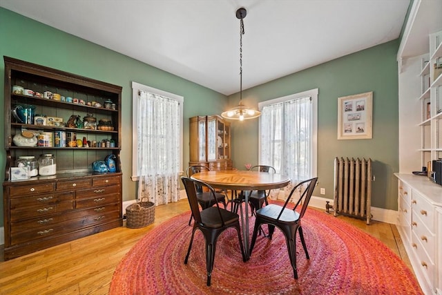 dining area with baseboards, light wood-style flooring, and radiator heating unit