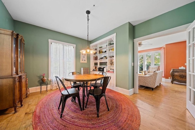 dining room with light wood-type flooring, a ceiling fan, and baseboards