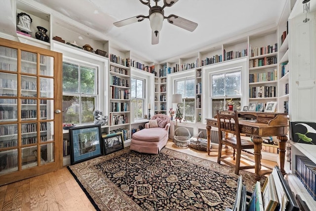 sitting room featuring ceiling fan, built in shelves, and hardwood / wood-style floors