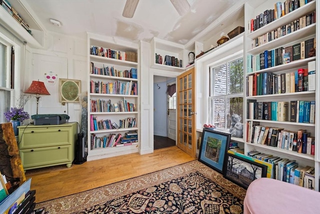 sitting room with french doors, built in features, and wood finished floors