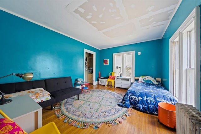 bedroom with radiator heating unit and wood-type flooring